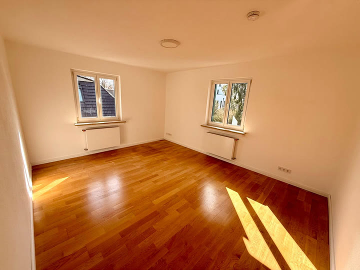 Helles, leeres Zimmer mit Parkett und zwei Fenstern nach einem Umzug